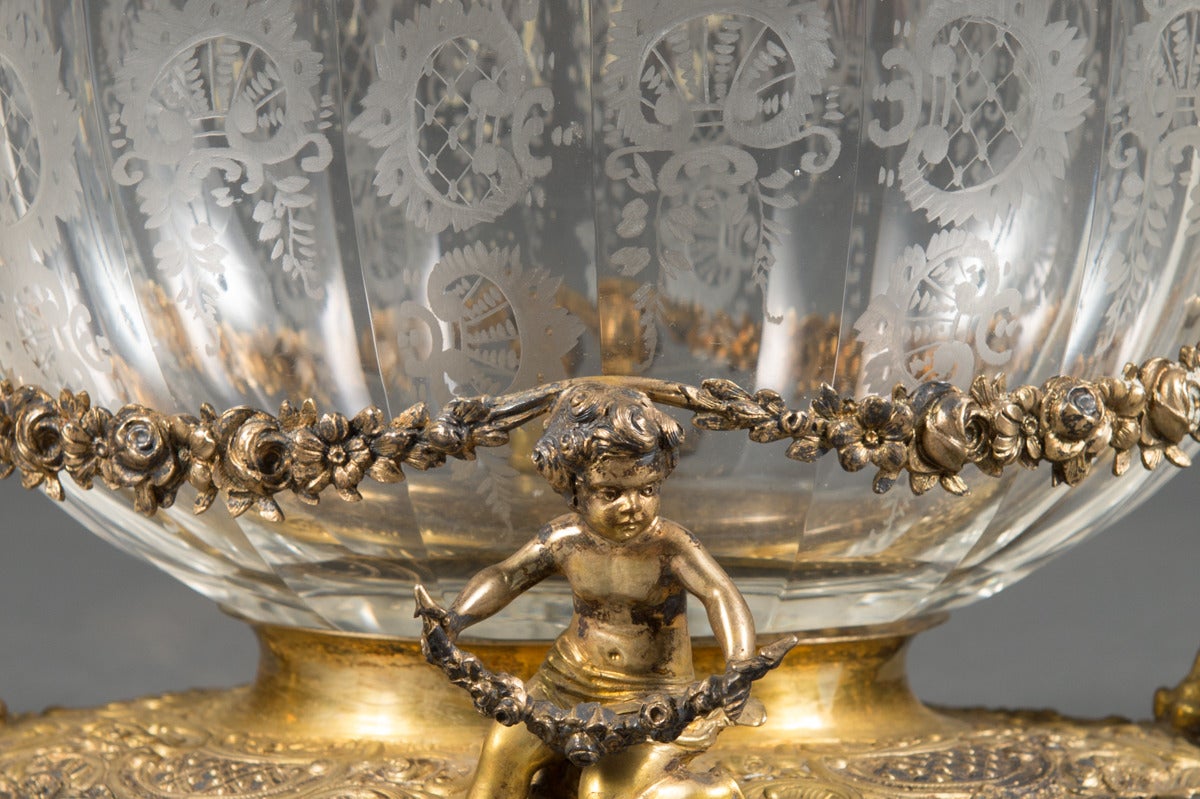 A 19th century German parcel gilt silver and crystal 3-piece garniture set comprising a centerpiece and pair of compotes, each cast with four putti and supporting etched crystal bowl.

Circa 1880

Centerpiece:
Height: 6