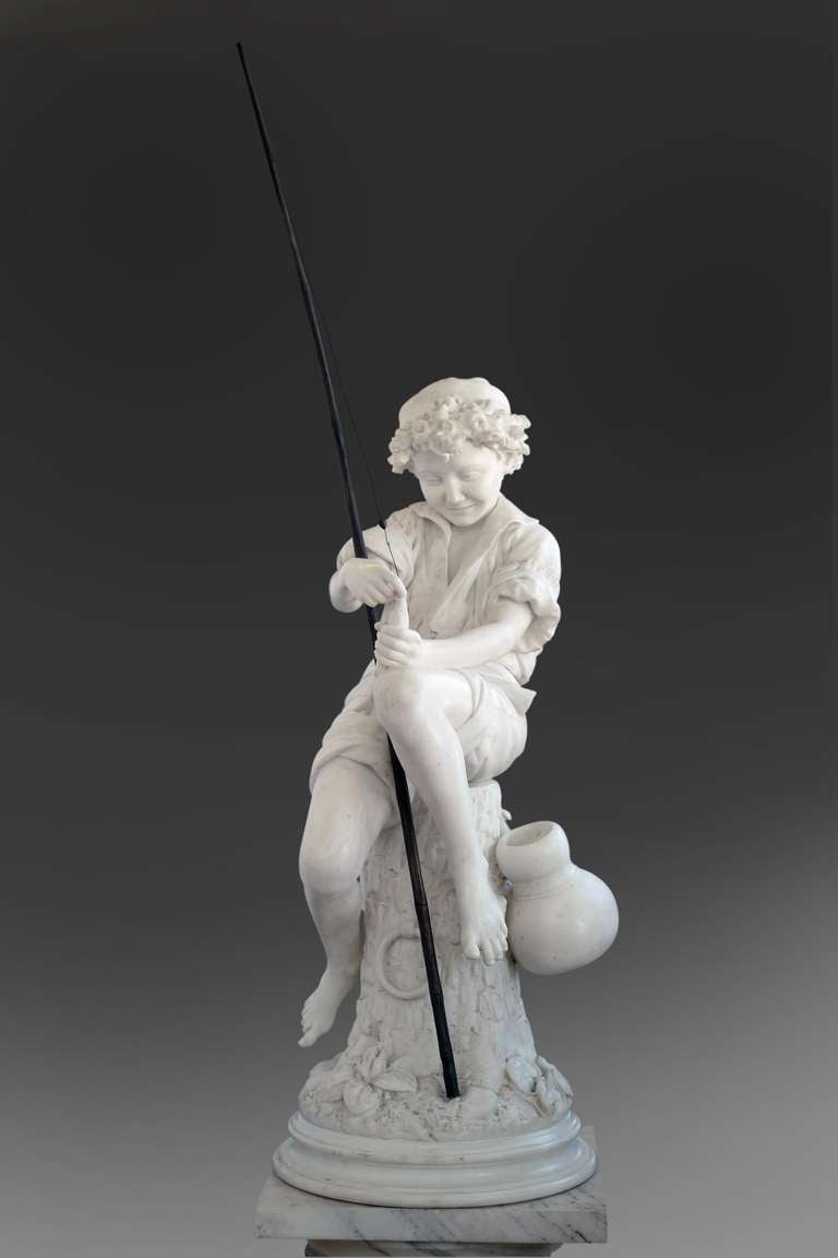 A masterfully carved 19th century Italian Carrera Marble figure of a fisherman boy holding a bronze fishing pole sitting on a stump with a satchel hung on a nail while holding a fish and removing the hook off the fish's mouth. Set on a circular