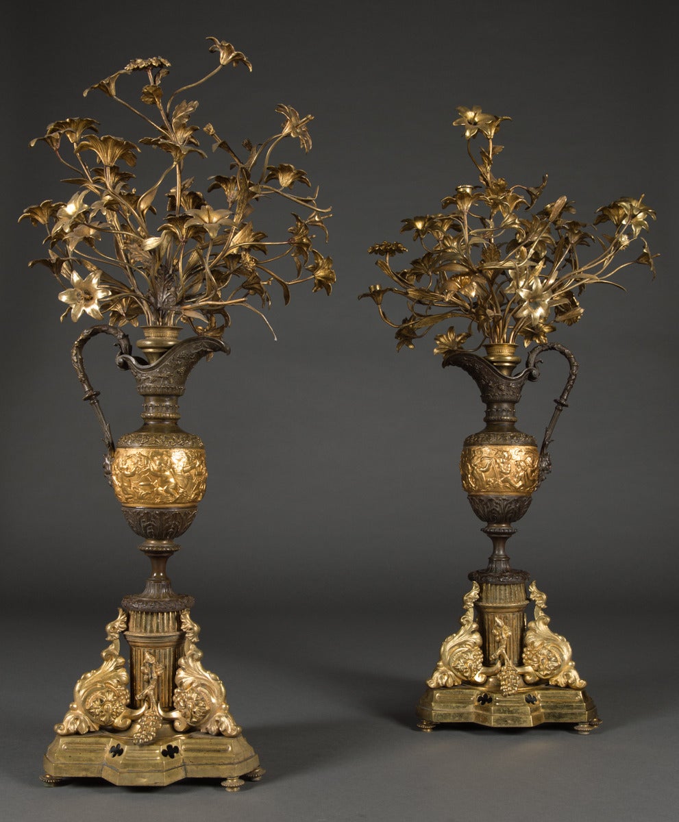 A Pair of large Antique French Gilt Bronze & Patinated Vase Form Candelabras.

Each with a vase form shaped body with central relief under a 12 branch candelabrum. Standing on a triangle shaped gilt bronze base.

Height: 48