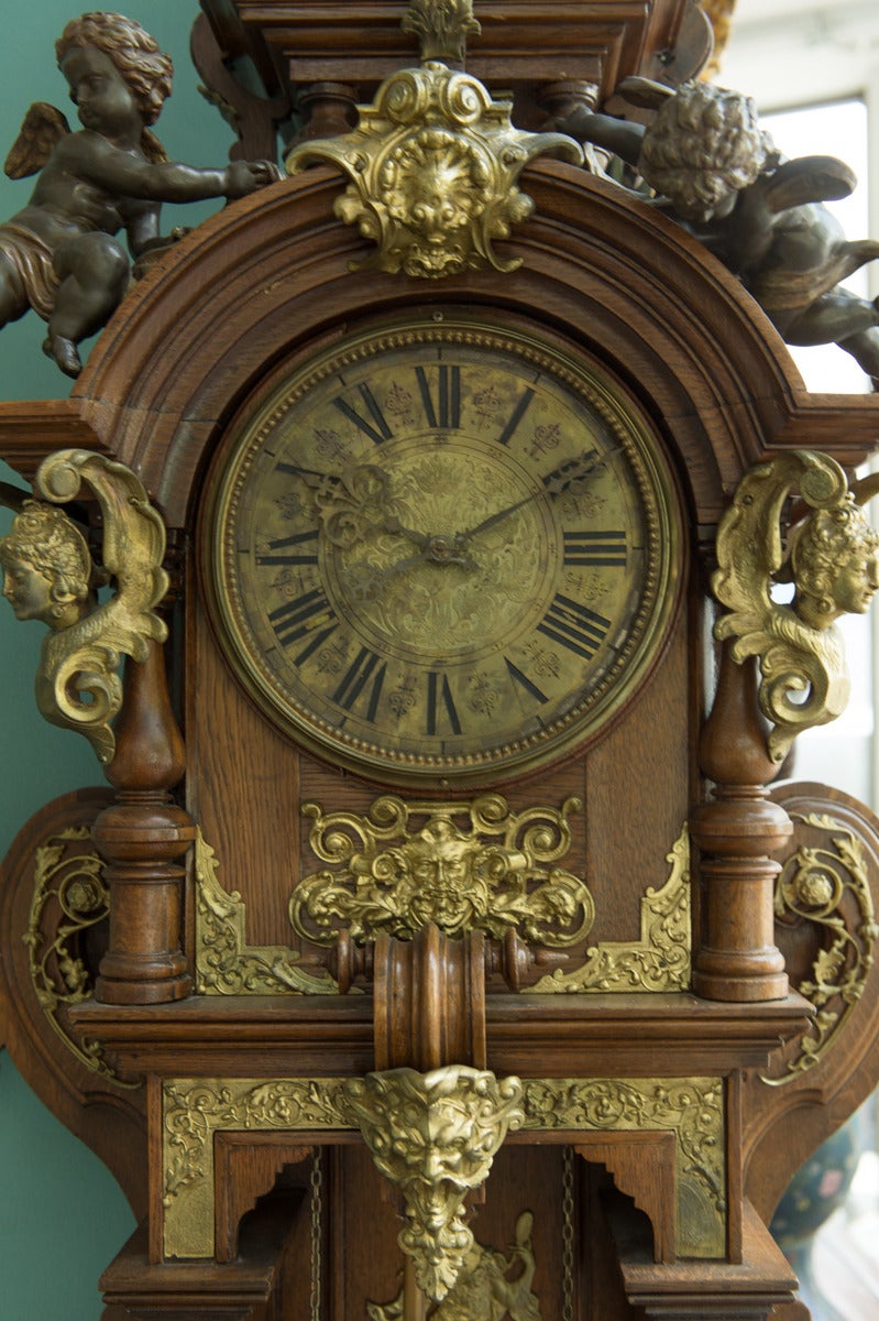 A Fine Austrian Antique Patinated and Ormolu-mounted Carved Oak regulator.

Having a tall and elaborate designed body surmounted with a pair of hovering patinated bronze figures of cherubs over an arched and molded brass clock face with Roman