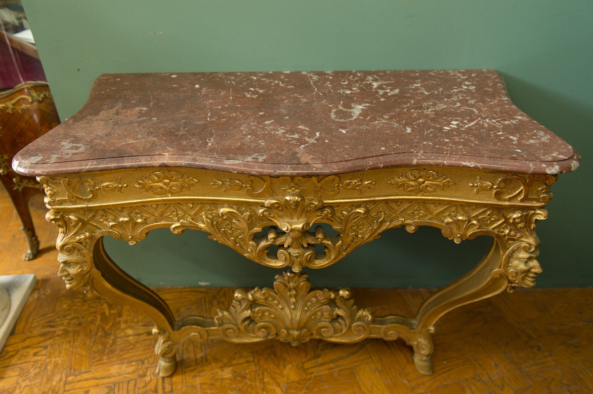 An Italian Antique Carved Gilt-Wood Louis XV Style Console Table

Having a Rouge Marble top over a pierced frieze centred by a rocaille motif and scrolling foliage with cabriole legs terminating in hoof feet. 

Height: 35