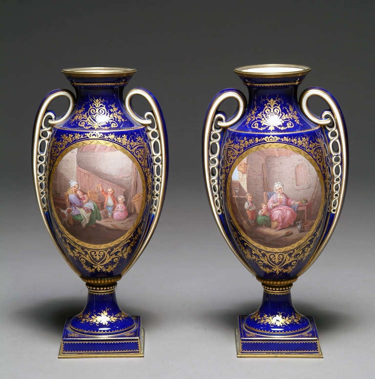 Dieses hübsche Paar Porzellanvasen im Sèvres-Stil zeigt auf der Vorder- und Rückseite fein ausgearbeitete Szenen. Die Vorderseite jeder Vase mit handgemalten Szenen einer Mutter und ihrer Kinder in einem Innenraum, die Rückseiten mit einer Hütte und