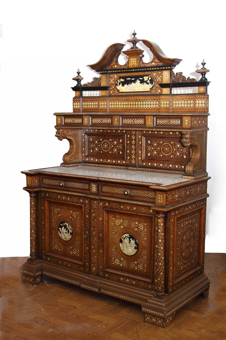 A Fine Late 19th Century Italian Mass Inlaid Walnut Commode/Credenza

The shelved superstructure with pediment surmounted by finials, fitted with four small drawers, on lion head supports

The lower section inset with a marble top above two