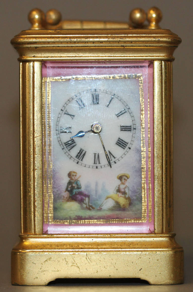 A French miniature gilt-brass and four panel porcelain-mounted eight day timepiece carriage clock. 
The corniche case with Sevres style painted porcelain panels to all sides depicting figures and landscapes, a gilt frame and blue borders, dial with