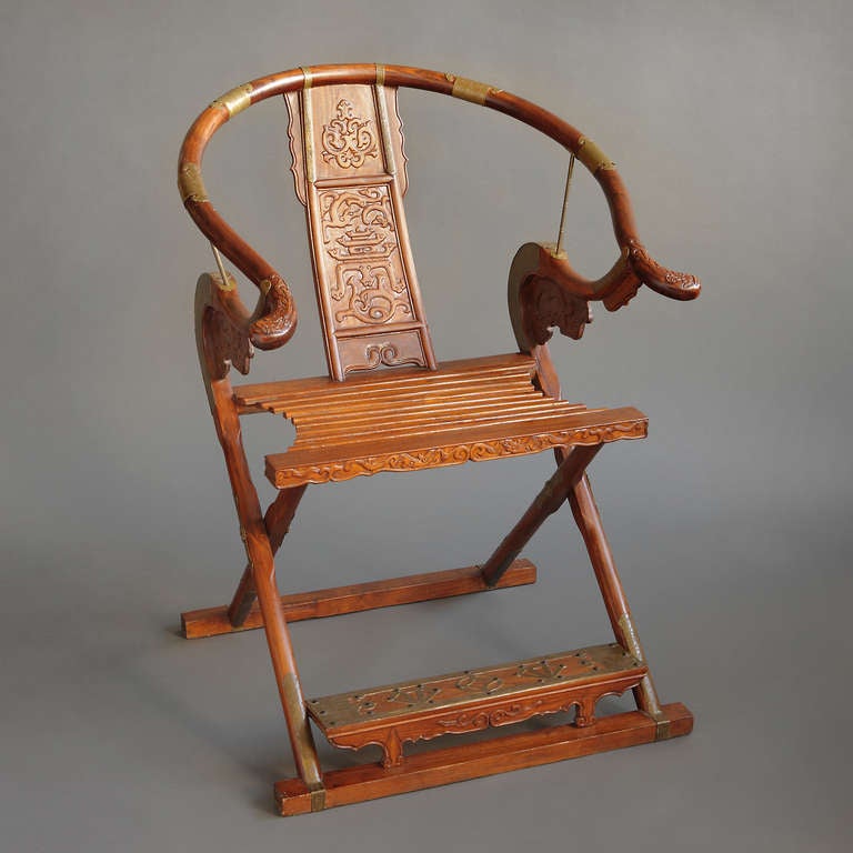 Pair of large Chinese brass mounted hand carved wood horseshoe shaped folding chairs. The round toprail, continuing in a curve to the arms and terminating in the out swept ends, supported by the hooked upper extension of the front leg, and a pierced
