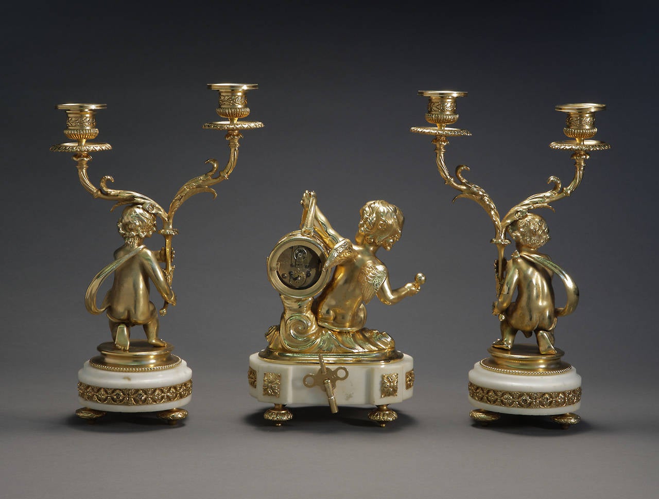 A French Louis XVI Style Ormolu Bronze Clock Garniture

Having an enamel dial with arabic numbers accompanied by two candelabras with cherubs on white marble bases

France, Circa 1880

Dimensions: Clock: 9