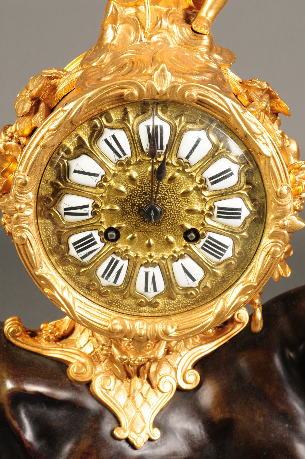 A Louis XV Style Gilt & Patinated Bronze Bull Mantel Clock.

French Circa 1880

Having 3¾-inch twelve-piece enamel cartouch dial with a bell striking Marti movement with an outside count wheel. The drum surmounted by Cupid and mounted on the
