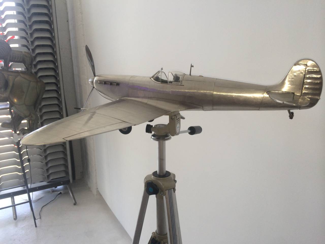 Wonderful 1980s scale model airplane, aluminum with 1940s tripod. Wheels under the airplane can be folded in. Tripod can be adjusted at the swivel and also in height up to approximately 70 inches.