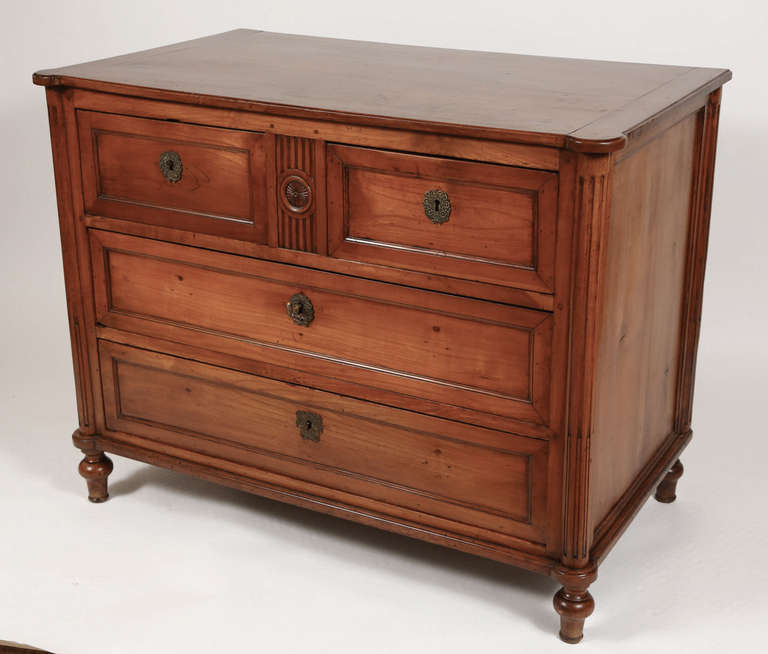 18th century French cherry commode with locking drawers, two small and two large, with brass hardware and key. Commode features fluted column stiles, turned feet, and carved rosette on front.