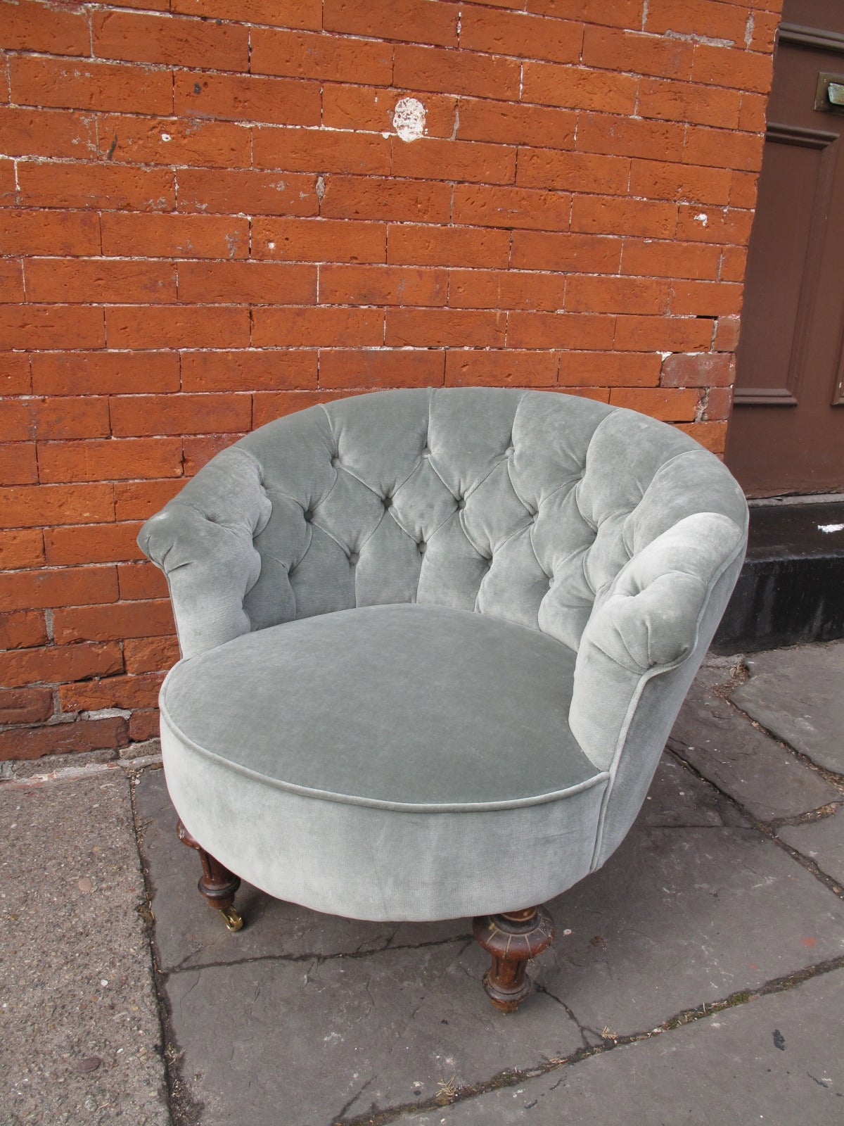 Petite blue velvet armchair on with rounded back. Small brass front castors. Newly reupholstered.
