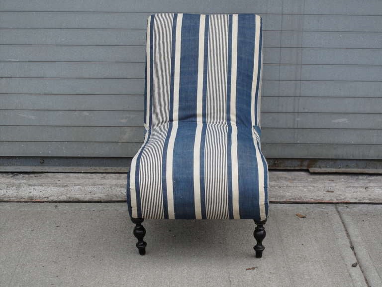 19th century French slipper chair, stripped down to the original blue and white ticking. Ebonized and turned front legs. Deconstructed to expose original leather strap supports on the back and burlap webbing on the underside.