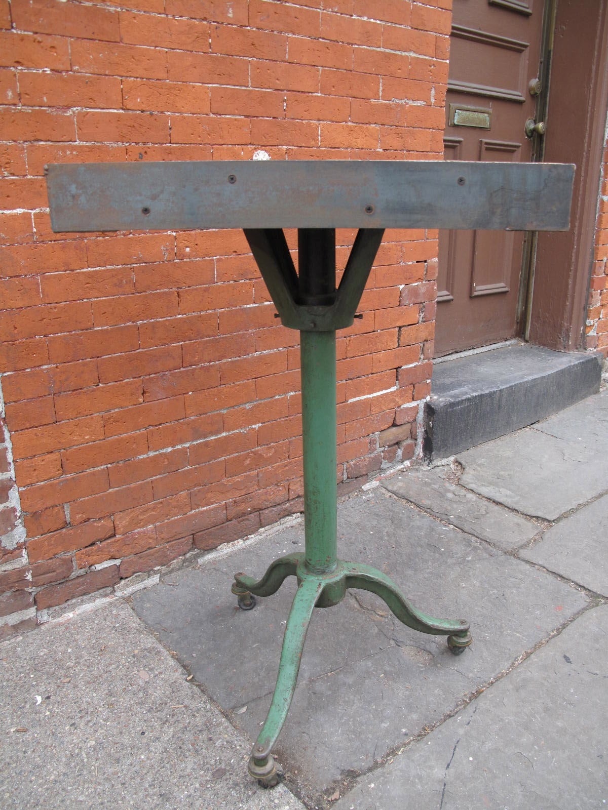 Industrial work table - strap steel-wrapped wood top on painted green iron base with casters.