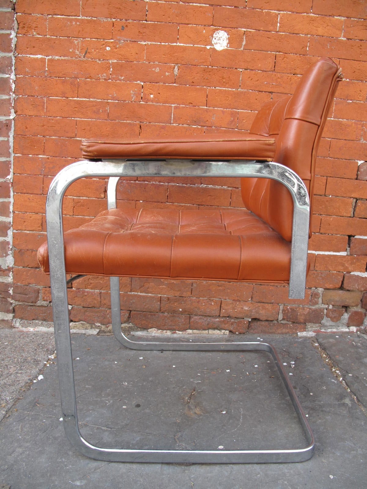 Midcentury modern arm chair by deSede. Chrome ribbon steel frame. Padded leather armrests. Slightly distressed orginal leather.