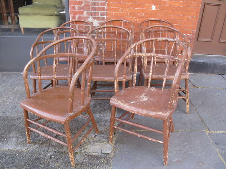 Eight comb-back armchairs in distressed brown paint.  Sold as a set.