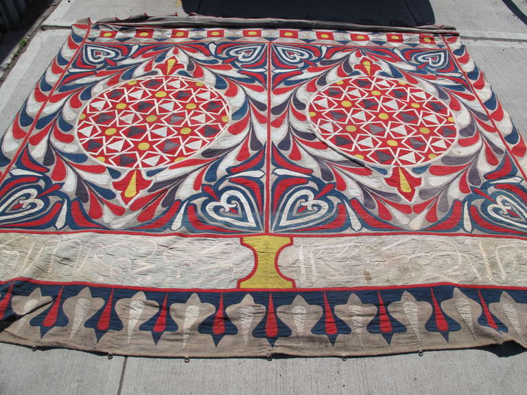 Side panel from an Egyptian market tent. Symmetrical design featuring two central medallions. One continuous weighted metal bar runs through the bottom hem. The top edge has original metal rings used to attach each panel to the tent frame or to one