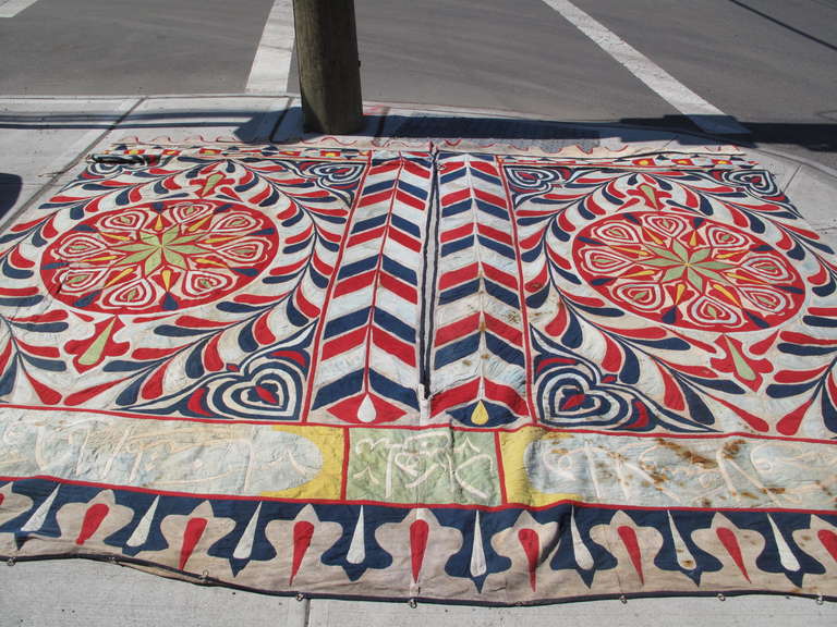 Intricate symmetrical appliqué design. Cotton and other natural fibers. Entirely stitched by hand. This panel was the front or entrance of the market tent and has a hemmed central opening. Each side has a separate weighted metal bar sewn into the