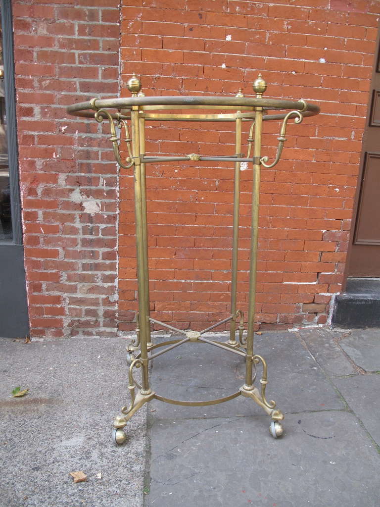Round brass rolling clothing rack.  Most likely out of a boutique or hotel.  Matched pair available individually.