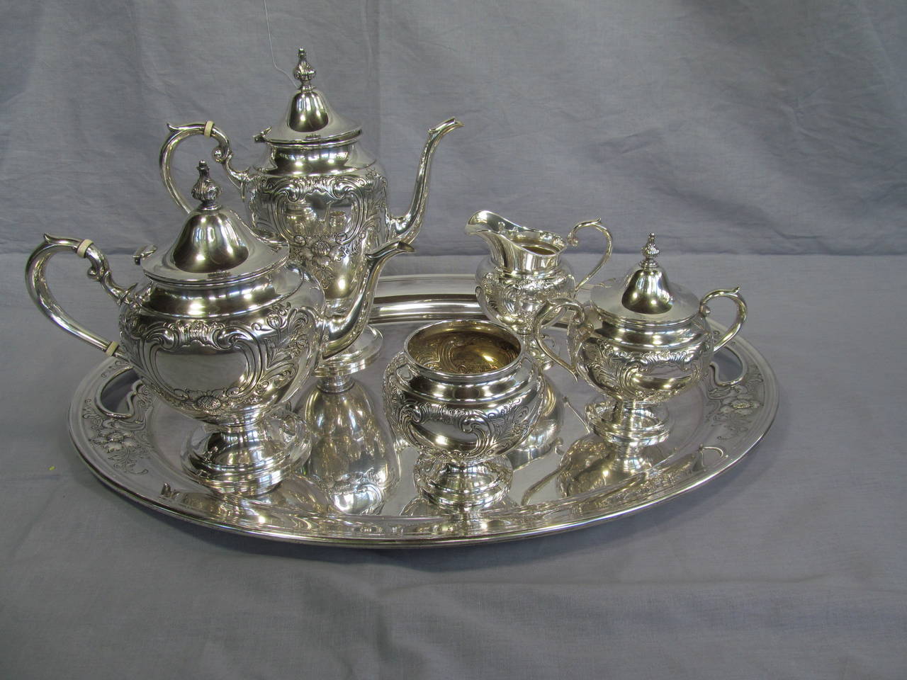 Six piece set including tray, coffee carafe, tea pot, cream pitcher, waste bowl and sugar bowl. Hand chased. 

Only hand polished. Some evident wear to gold wash interior. 

From the Estate of Mark Lee Kirk, Art Director at 20th Century Fox in
