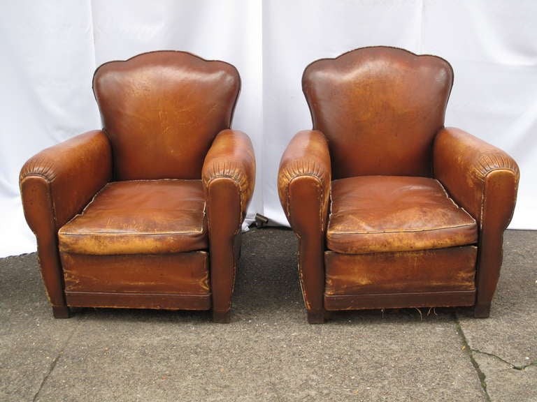 Clover back leather club chairs.  Rich patina.  Original cushions.  Pleated detail on arm rest.  Block wood legs.