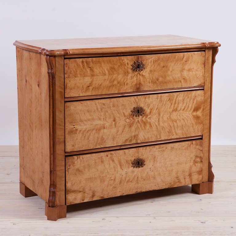 A very lovely chest in birch with three drawers that is a transitional piece between Biedermeier and *German Louis Philippe. Northern Germany, circa 1845-50. Has original carved wood key plates in the form of a garland. Comes with working locks and