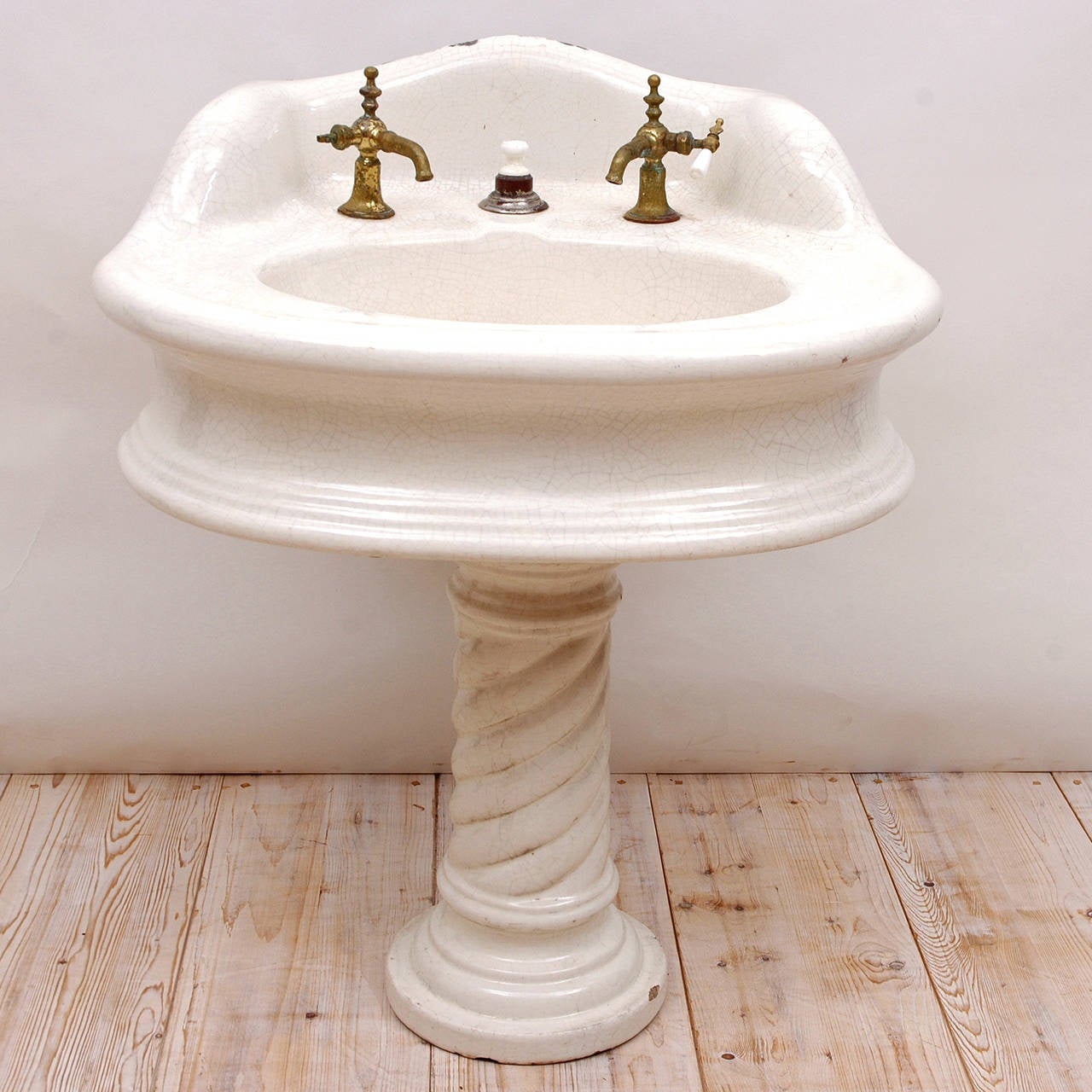 A beautiful & very sculptural Victorian pedestal sink in cast earthenware with white porcelain glaze, circa 1880. Includes old brass faucets & stopper. Porcelain sink is crazed but not structurally compromised. There are some chips on the pedestal.