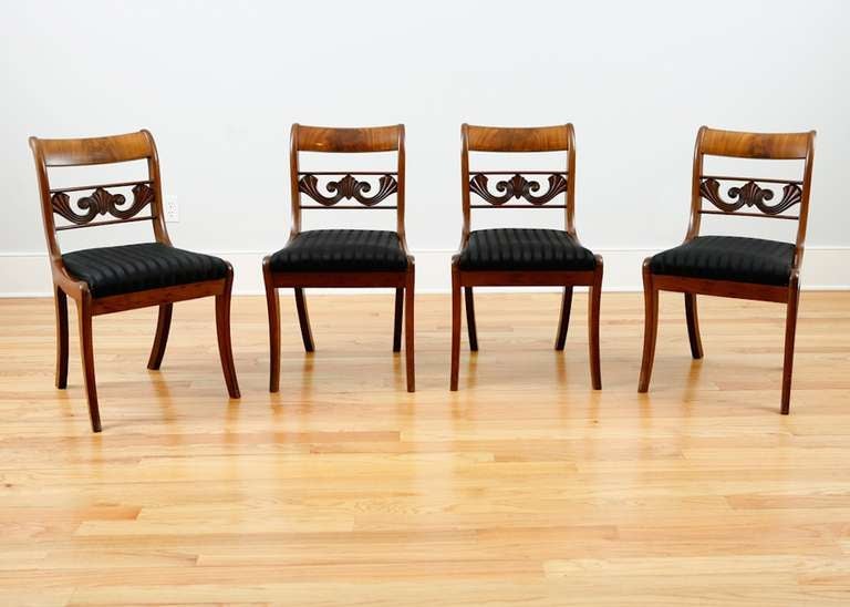 Set of four English Regency dining chairs in mahogany with carved and pierced back, slip seat and saber legs, circa 1830.
Measures: 19