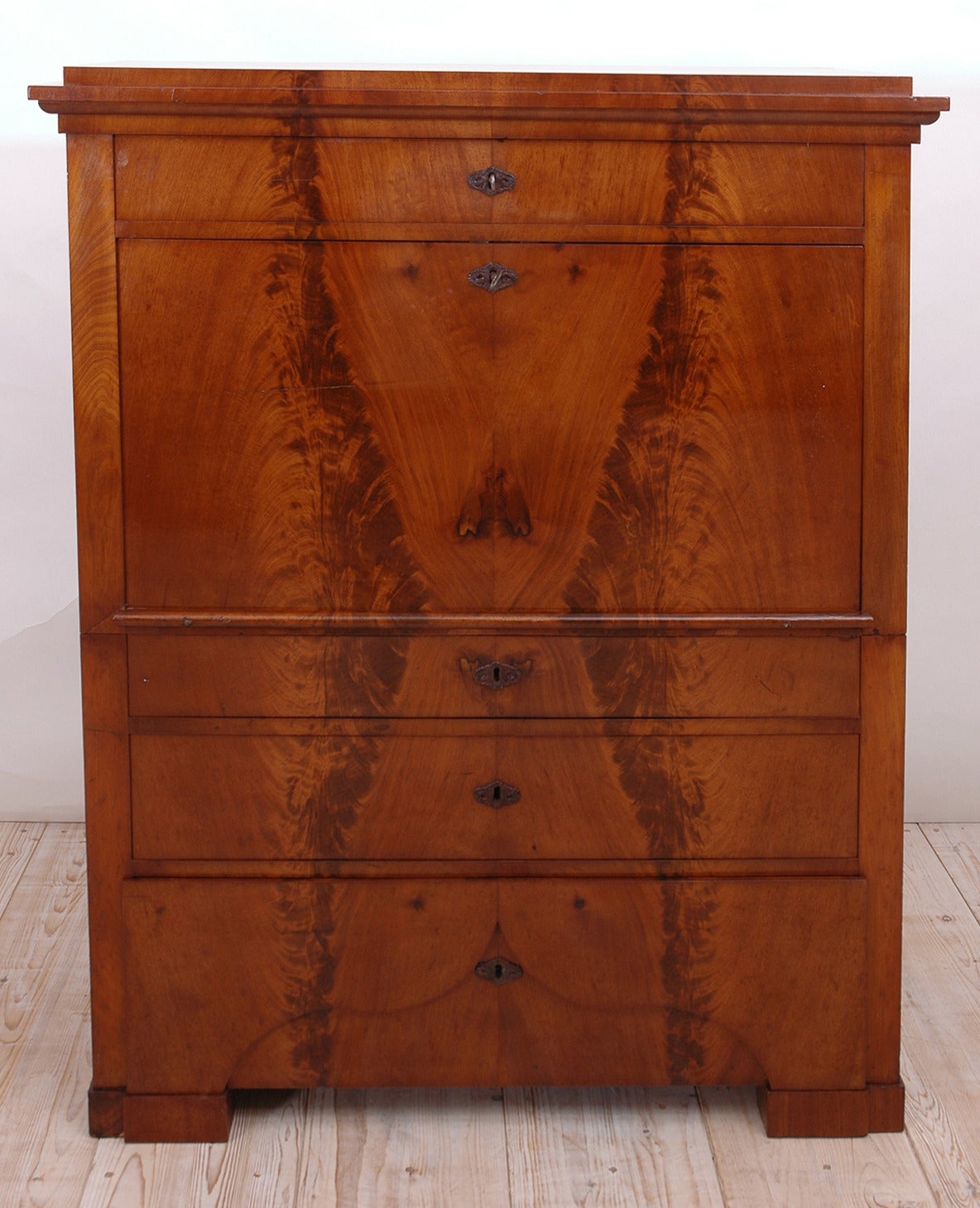 A very fine Biedermeier secretaire in beautifully book matched flame West Indies mahogany with fall-front opening to an ample desk surface with one long exterior drawer above, and three drawers below, each of staggered depths. The interior offers a