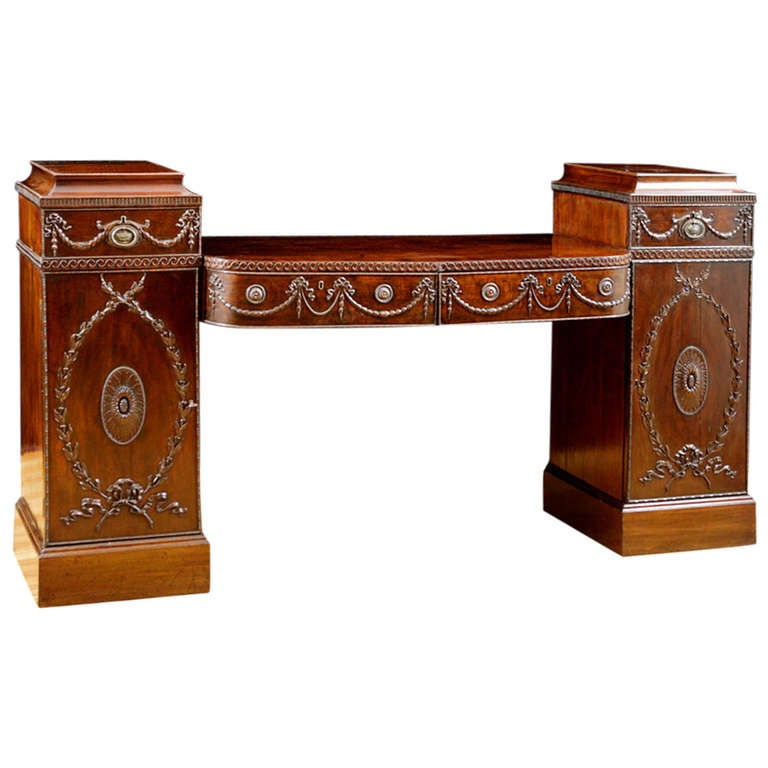 Pedestal base mahogany sideboard in the style of Scottish neoclassical architect Robert Adams, with carved swags and rosettes. Features four drawers and two cabinets. Interior cabinet has one spirits drawer and shelves.

Measures: 83 1/2