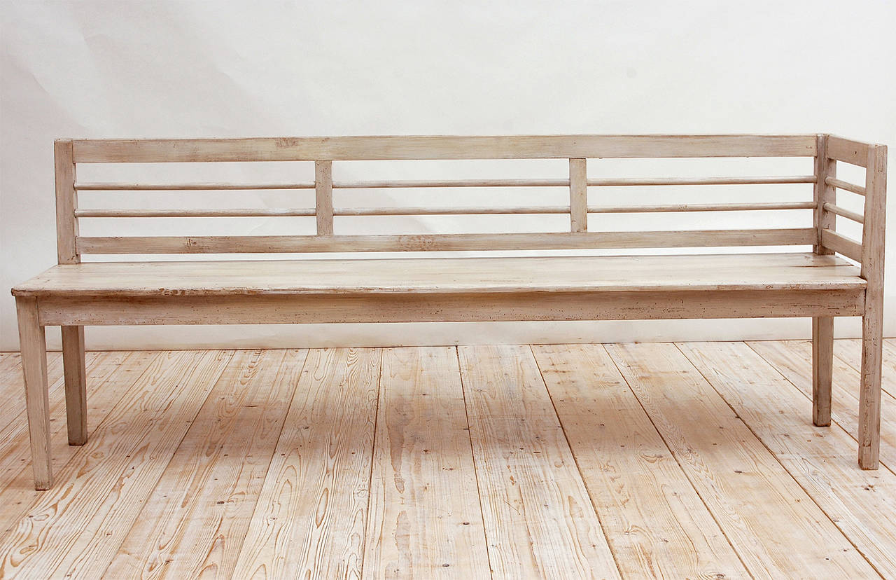 A long bench in pine with white/grey paint featuring a ladder-back extending to include one arm, and resting on square tapering feet. Scandinavia, circa 1900.
Bench is painted front and back so that it can float in a room if necessary.

86