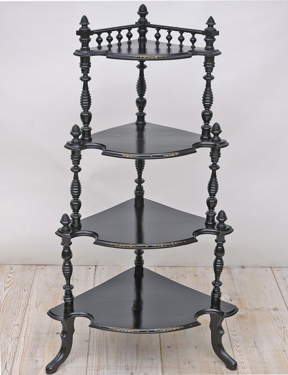 A lovely Napoleon III corner etagere or what-not in ebonized wood (original black painted finish) with turned columns and small decorative brass escutcheons. Offers four shelves supported by turned columns and rests on carved hoof feet, France,