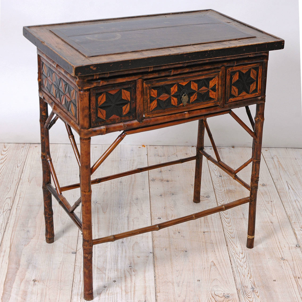 A very unusual and beautiful table in bamboo embellished with a geometric design in various wood inlays along the apron and fascia of drawer. Top is inset with a japanned section of wood. Continental Europe, circa early to mid-1700s.

Measures: