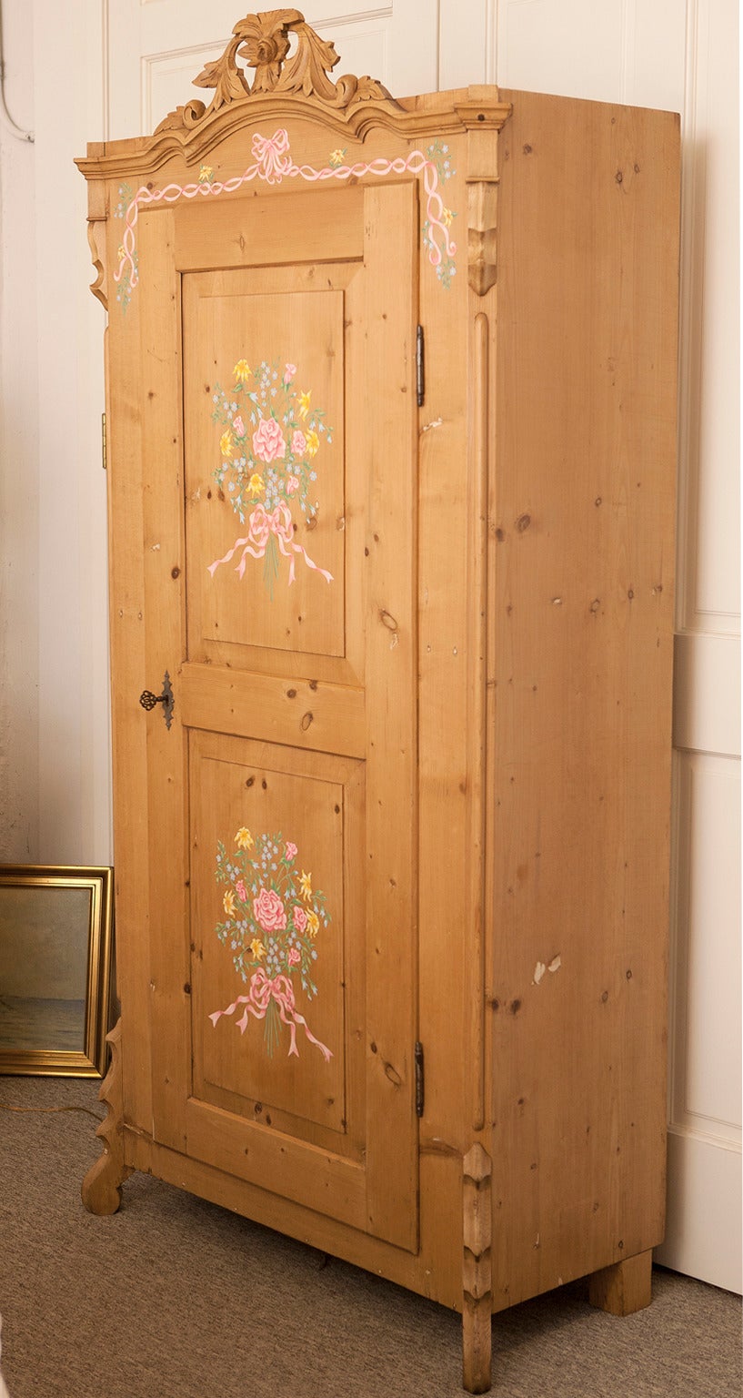 Louis Phillipe German single door armoire offers a lovely carved bonnet with a central flower and foliage, carved feet, a and single door that opens to three and a half interior shelves.