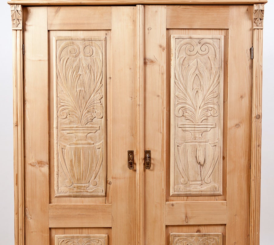 From the Austro-Hungarian Empire, this charming, armoire offers carved urns depicted on each of four bass wood door panels (seldom seen on a pine armoire), foliate carvings on corners and frieze as well as the bonnet. Interior offers a vertical