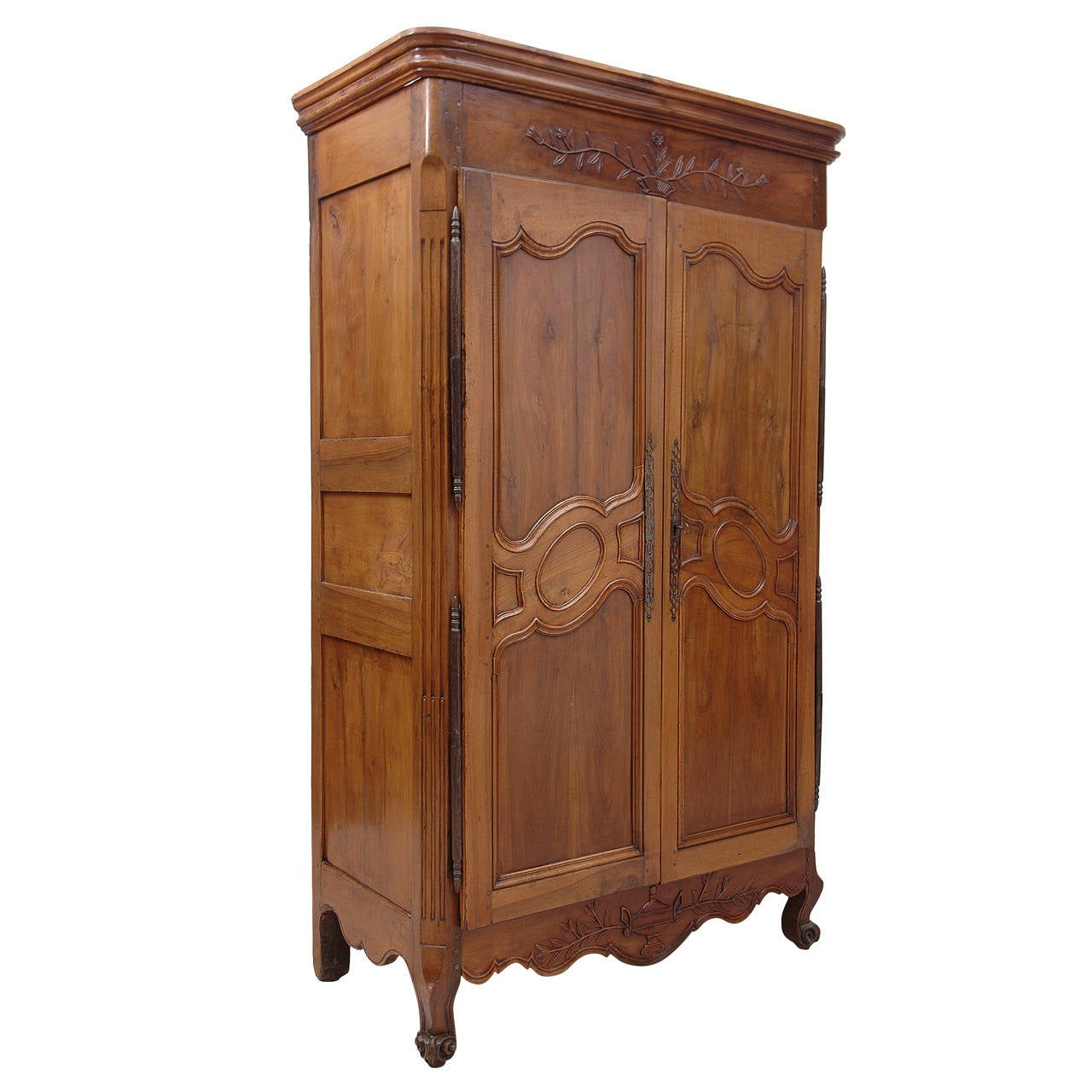 A French armoire in walnut from the late 1700s with carved foliage and urns in relief on the frieze and the bottom apron. More recent custom cabinetry in the interior offers sixteen clothing drawers ranging in depth from 3.5