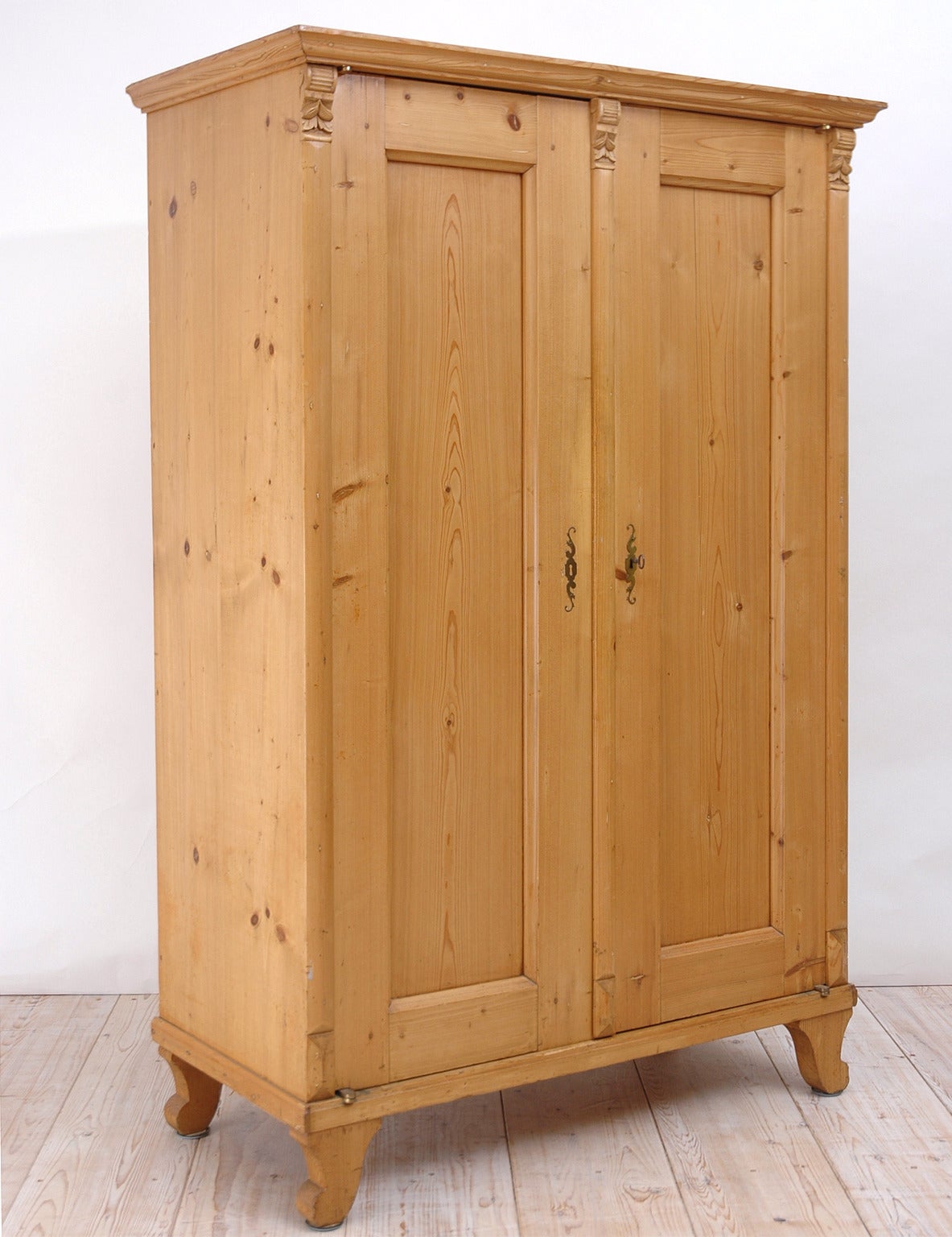 From the Austria-Hungarian Empire, a beautiful small armoire in pine with two doors opening to an interior outfitted with fixed and adjustable shelving and one small drawer. Knife hinges were added to allow the doors to open 180 degrees (flush with