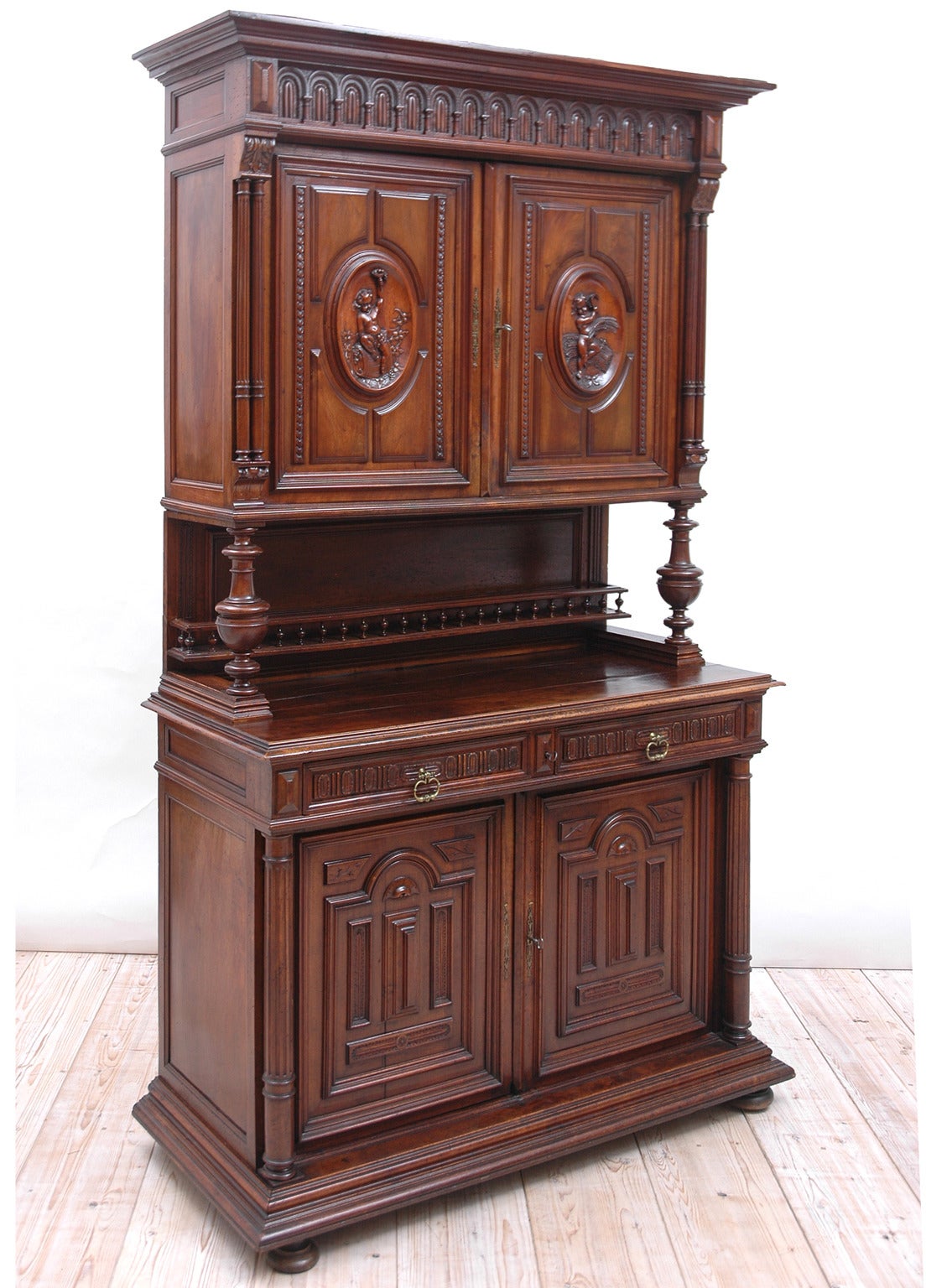 A lovely Belle Époque buffet in walnut in the style of Henri II of France with carvings of putti on the upper door panels, one holding a sickle and a bundle of wheat, and the other resting on a wine barrel while holding a cornucopia of grapes.