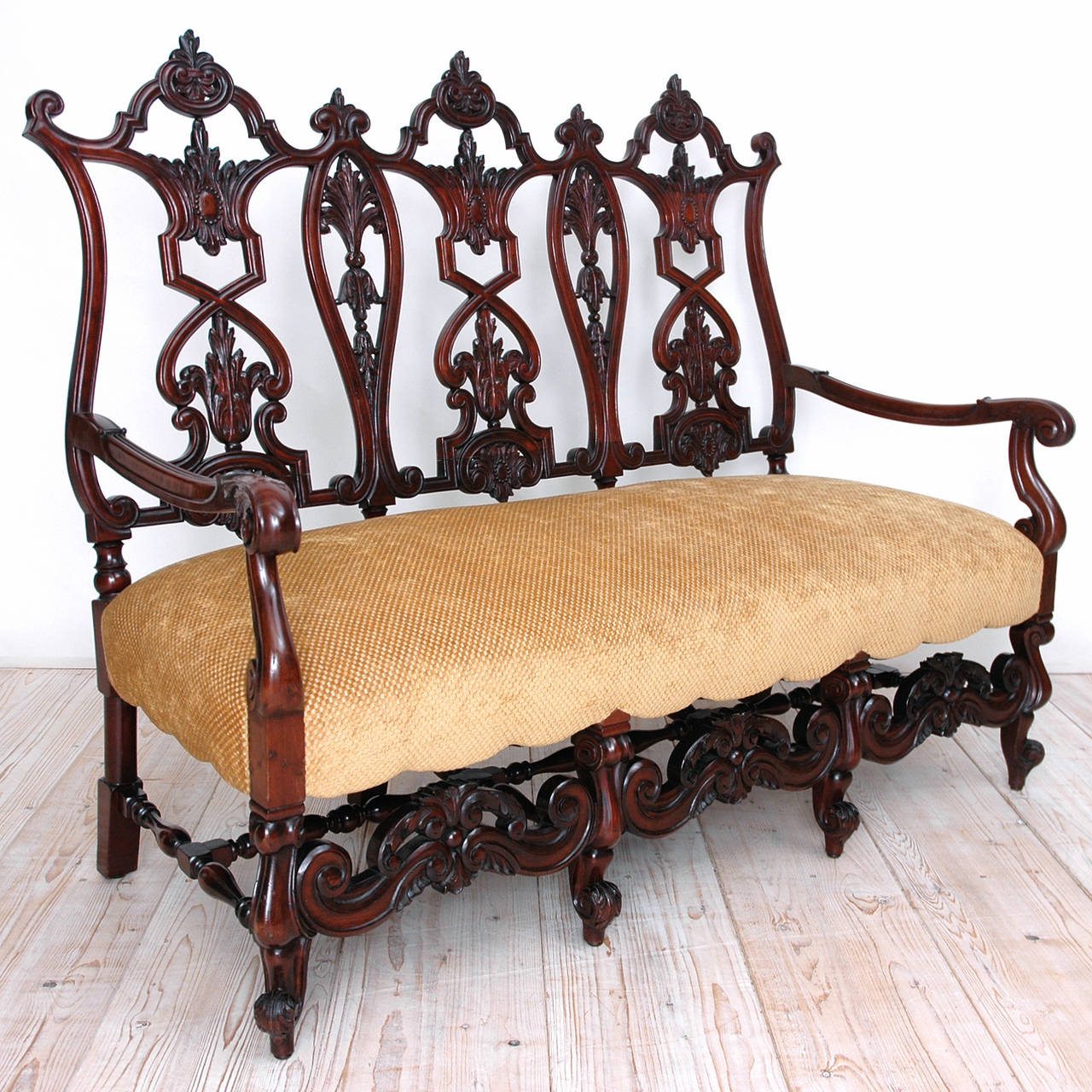 An exceptionally beautiful settee with upholstered seat and carved mahogany frame embellished with acanthus and fleur-de-lys motifs, carved scroll arms and escargot feet. Seat is upholstered in gold-colored chenille fabric, American, circa