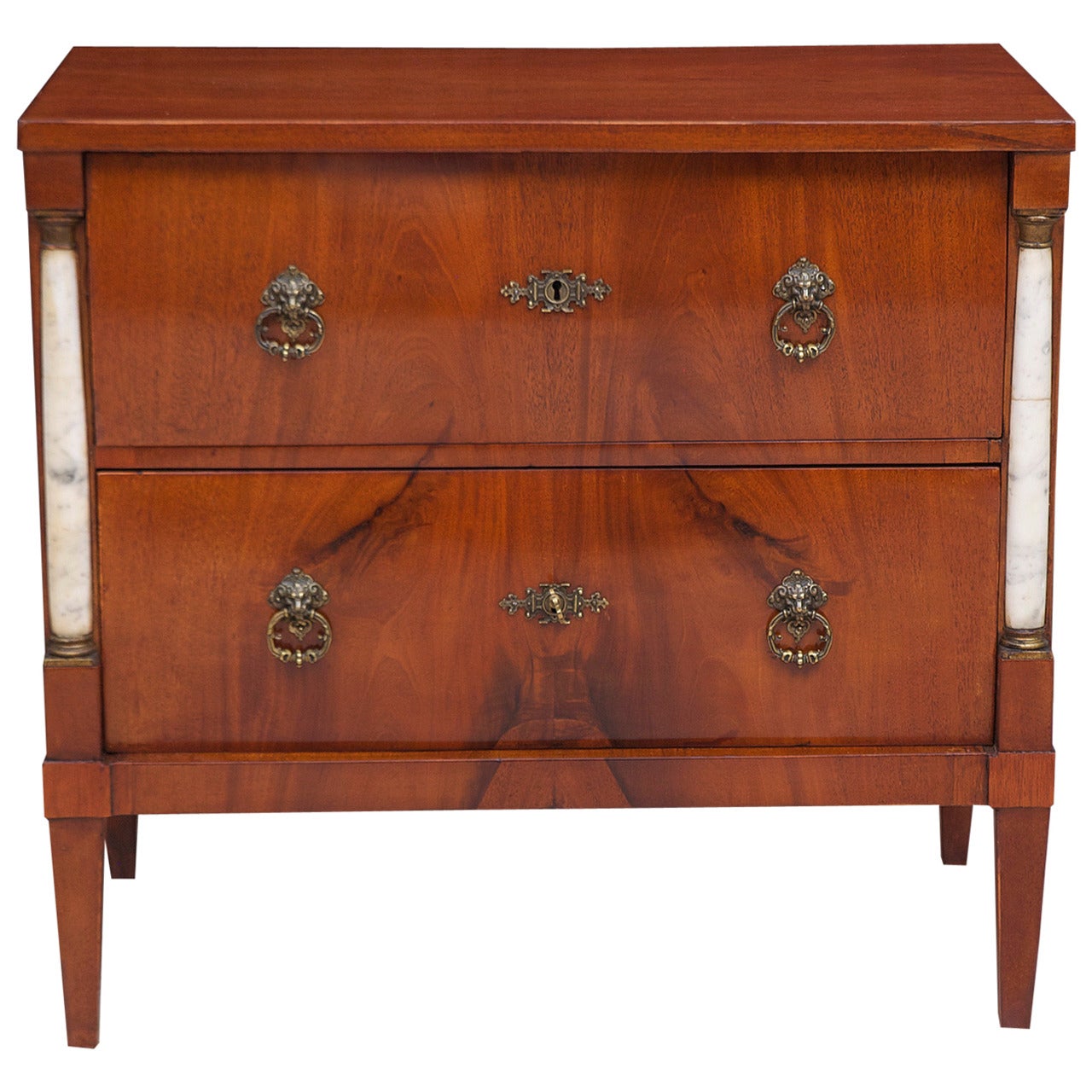 A beautiful Empire commode in Cuban mahogany with marble columns flanking two drawers and resting on tapered square feet. Brass key plates and pulls were added in the late 1800s. French-polish finish. Comes with one key that operates both drawers
