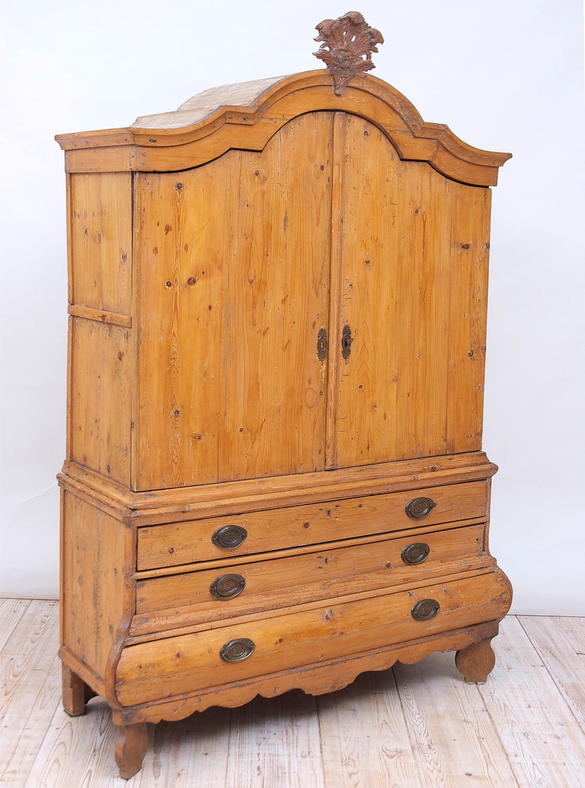 A very lovely and diminutive linen press or kast in pine from Holland with bombe front, offering two cupboard doors over three long drawers with carved bonnet and resting on the original feet, Dutch, early 1700s.

Dimensions: 58