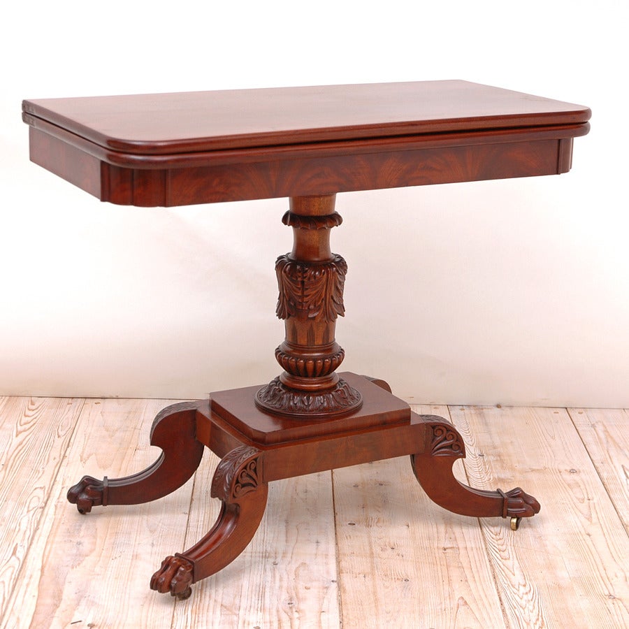 An exceptionally handsome and very well crafted classical Philadelphia Federal games table in premium mahogany with turned and finely carved pedestal on quatre-form base, with carved saber feet ending in lion’s paw. Top opens and pivots to a square,