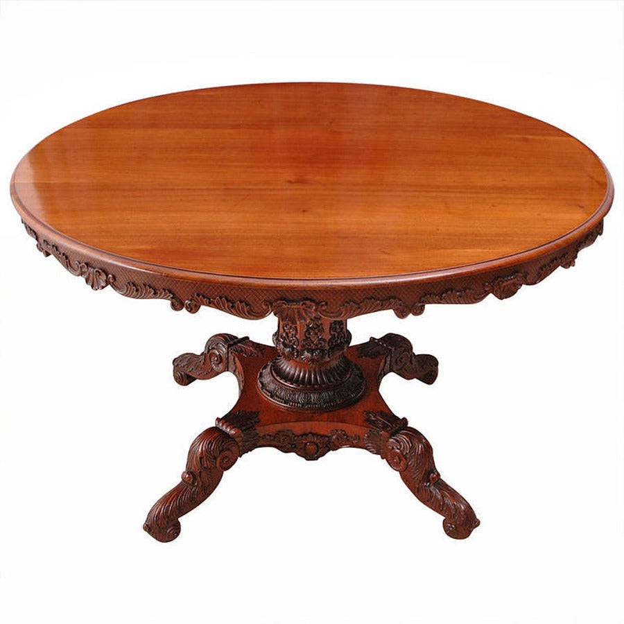 A magnificent English Regency dining table in mahogany with round top and turned and beveled column on quatre-form base ending in 