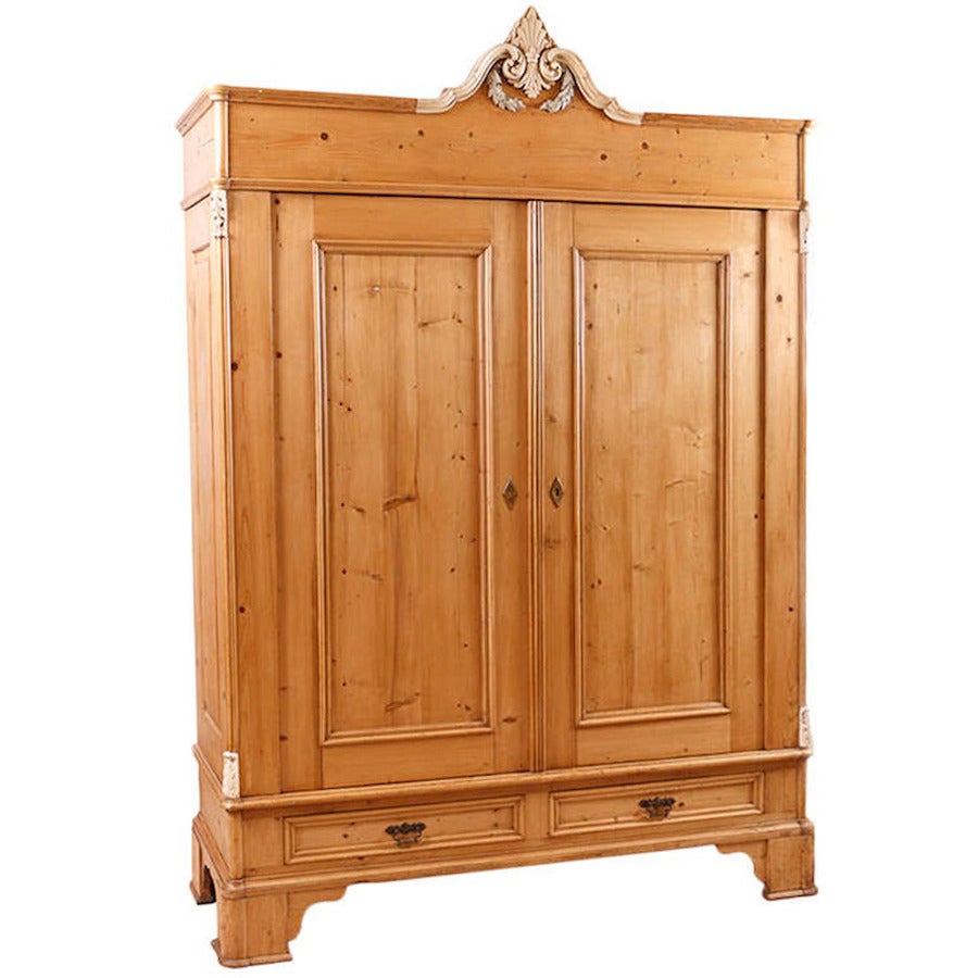 An unusually large pine armoire with high bracket feet which are typical of the Hamburg region and original molded plaster embellishment on arched bonnet. Offers two small bottom drawers and three adjustable shelves. Northern Germany, circa