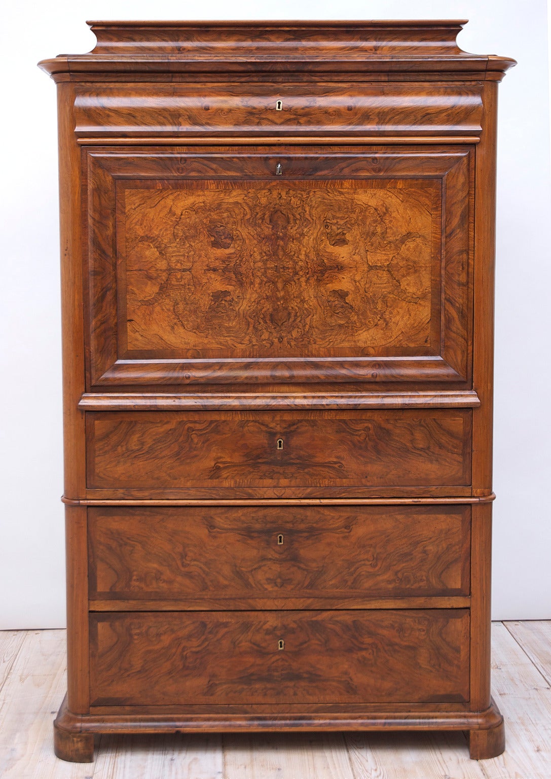 An exceptional Biedermeier Secretary in book-matched figured walnut and burled walnut with one top drawer below pedestal top and three storage drawers of staggered depths below desk surface. Fall-front opens to a small central cabinet with a drawer