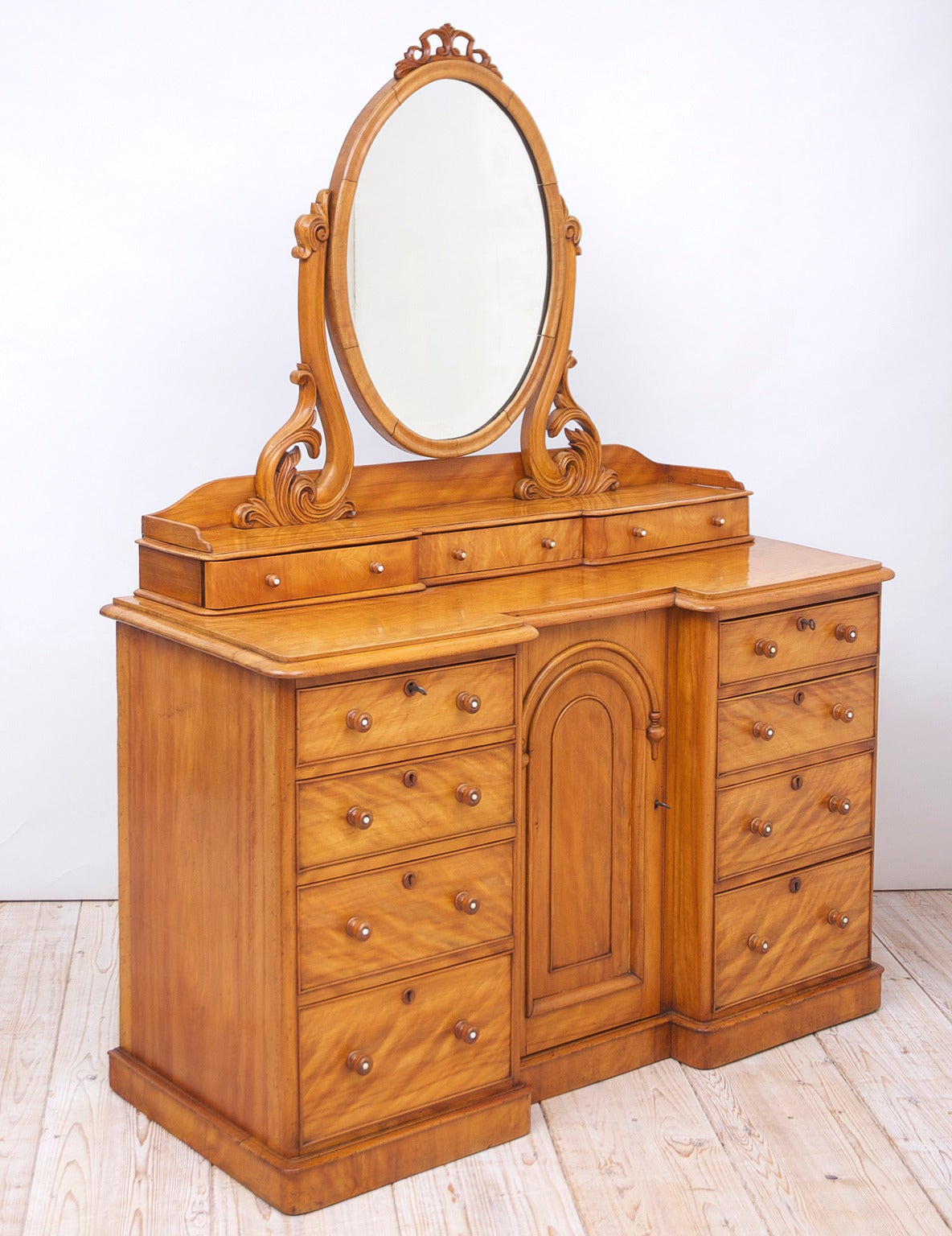 A beautifully crafted late Regency dressing table or chest with oval mirror in satinwood, featuring a plethora of drawers (eleven in all!) with a central cabinet. England, circa 1830. With a Fine attention to detail, this cabinet appears to have