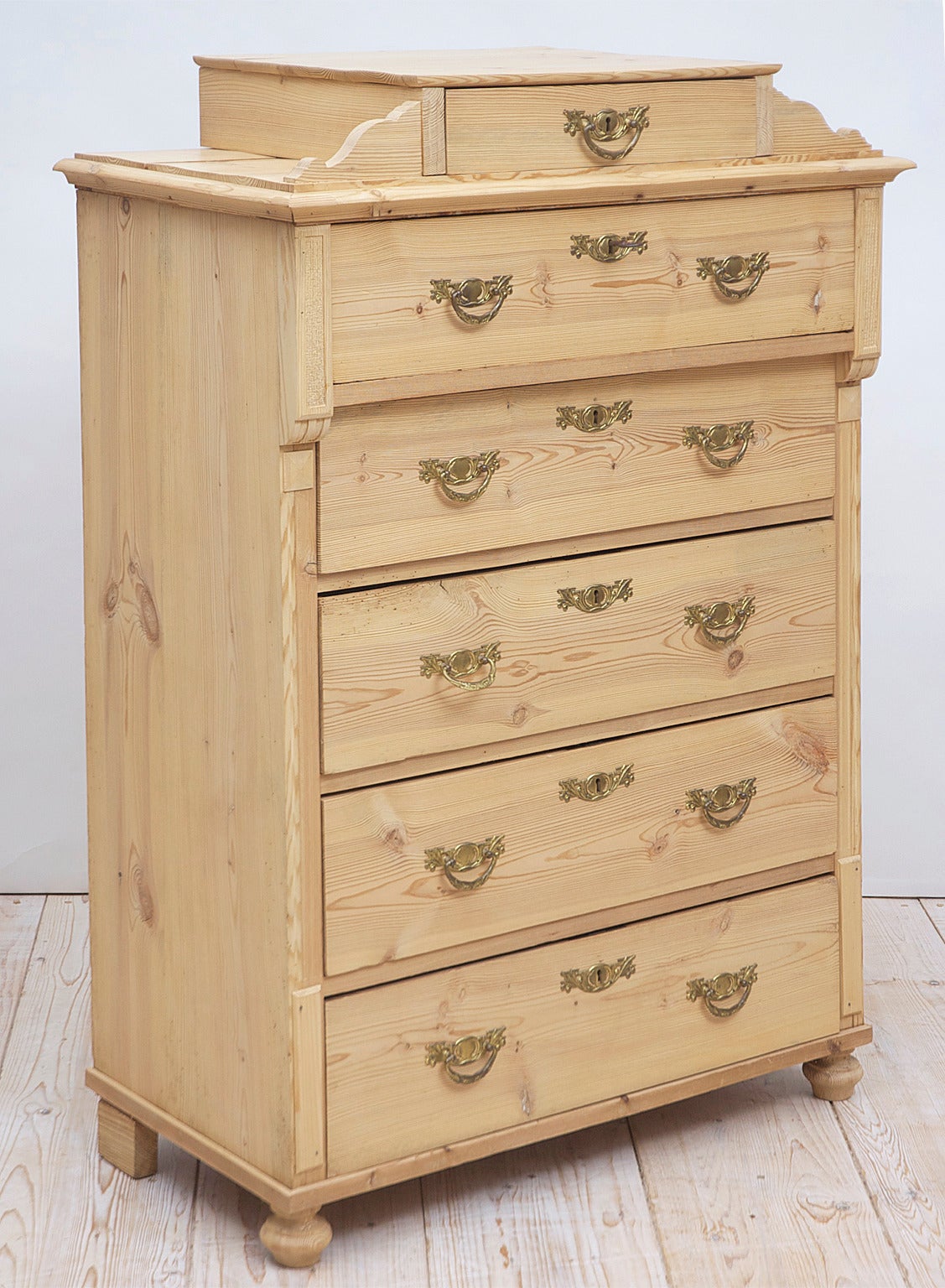 The finest Scandinavian pine from the Gründerzeit epoch. A charming chest of drawers in scrubbed pine with pediment top housing one small drawer, followed by full size five drawers. Offers original brass pulls and key plates and bun feet.
All of