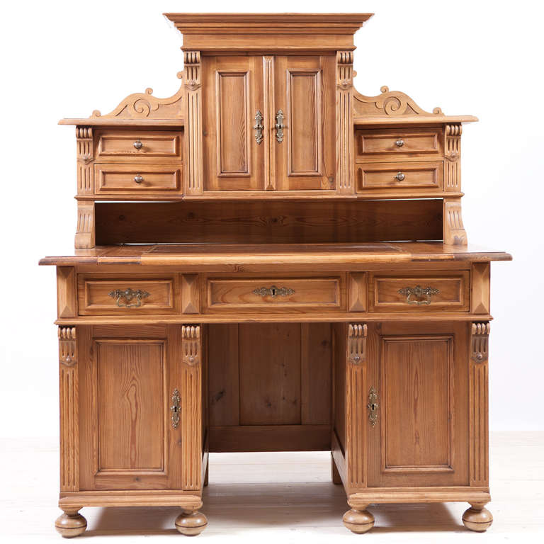 A handsome & spacious Gründerzeit pedestal desk in pine. Germany, circa 1880. Base offers a pull-out writing surface with brown-leather top with gold tooling around edge, a long drawer above kneehole and storage cabinets at either side. Top cabinet