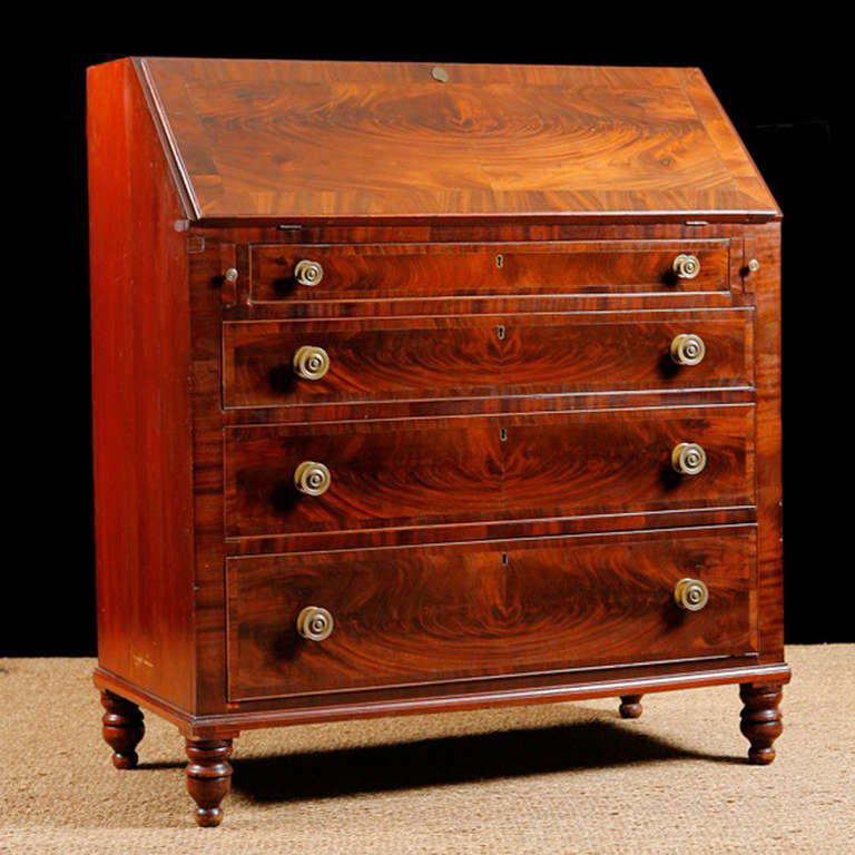 A Beautiful Lancaster County Slant Top Secretary in mahogany with book-matched mahogany veneer, original oxblood blush finish on interior desk surface and four staggered drawers, all resting on turned feet. Very fine, reproduction brass pulls have