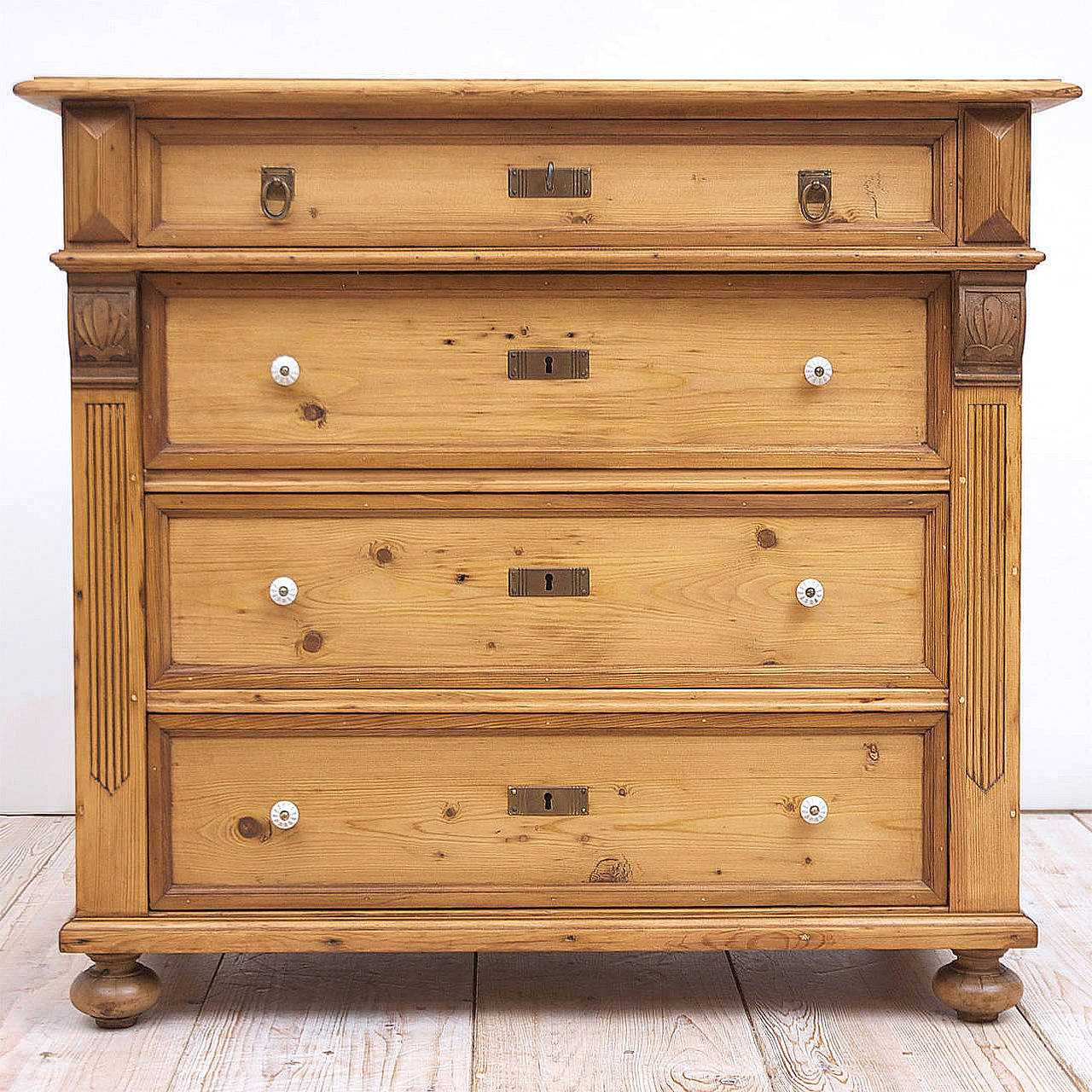 The finest period European pine from the Art Nouveau epoch, a chest
with four drawers of graduated depths offering original brass key plates and rings, working locks with one key and resting on original turned, bun feet. While antique, porcelain
