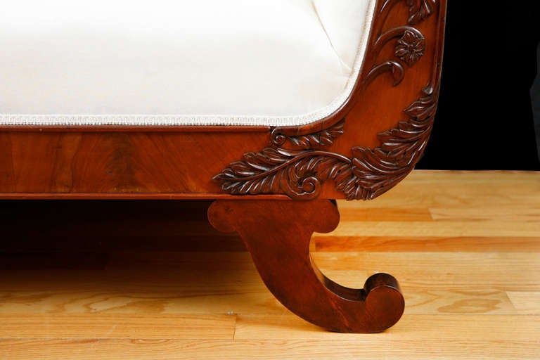Empire or Biedermeier upholstered sofa with a French-polished mahogany frame, Northern Europe (from either North Germany or Denmark), circa 1825. Well-articulated applied carvings of acanthus leaves on fascia of scrolled arms, with cornucopia feet