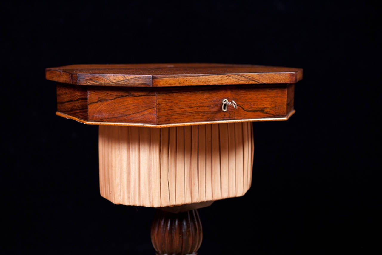 A small and graceful sewing or work table on carved tripod base with octagonal top in rosewood with satinwood floral inlays. Lift-top opens to lidded compartments with access to pleated-silk sewing basket. France, circa 1850.
Measures: 16 1/2